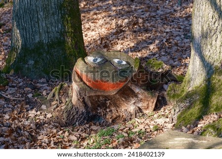 Picture of a treestump painted to resemble the face of pepe the frog