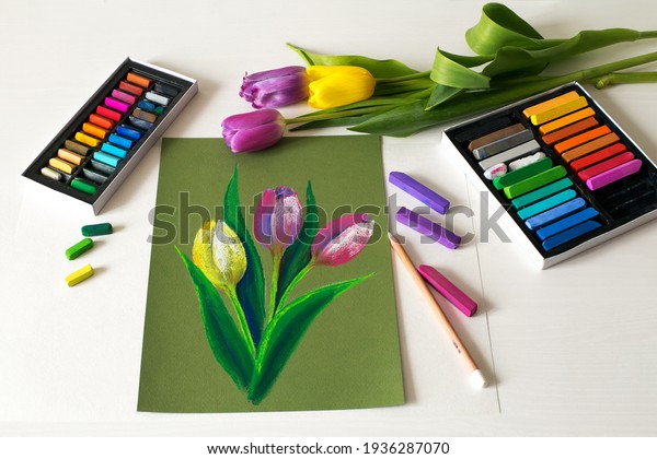 Picture of tulips.\
Soft pastel drawing, painting of flowers. Pastel drawing tulips on\
paper with hands. Top\
view