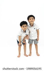 Picture Of Twin Asian Boys Standing Together With Funny Face On White Background. Looking At Camera.