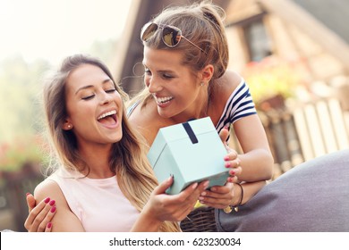 A Picture Of Two Girl Friends Making A Surprise Birthday Present