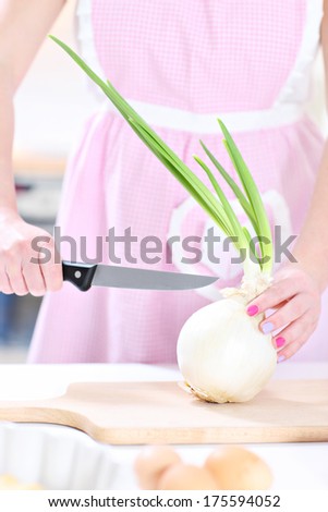 A picture of a woman cutting onion in the kitchen