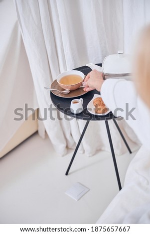 Picture of woman hand holding cup of tea on a table while enjoying good time at the breakfast in spa resort hotel