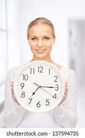 picture of woman holding big clock in office
