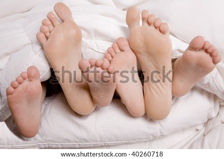 A picture of a woman and kids feet poking out of the covers.