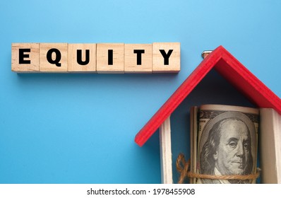 A picture of wooden block with Equity word, house miniature and fake money insight. Equity is the difference between the market value of your home and the mortgage amount. - Shutterstock ID 1978455908