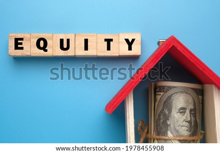 A picture of wooden block with Equity word, house miniature and fake money insight. Equity is the difference between the market value of your home and the mortgage amount.