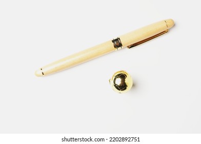 A Picture Of Wooden Pen With Golden Ball On White Background. Signing Good Player In Transfer Window Concept.