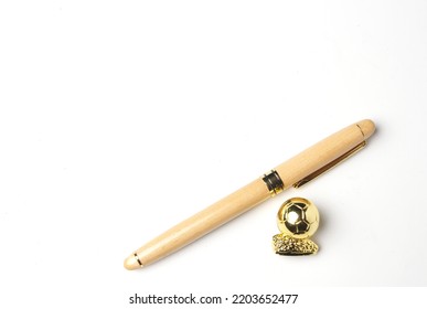 A Picture Of Wooden Pen With Golden Ball On Copyspace White Background. Signing Good Player In Transfer Window Concept.