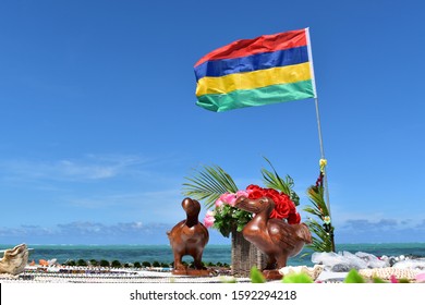 Picture of a wooden statue representing the symbol of Mauritius the Dodo bird. Mauritius flag in background. - Powered by Shutterstock