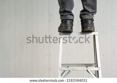 Picture of a worker standing at the top of the stairs. which is unsafe work because there may be an accident on the stairs can cause in jury.