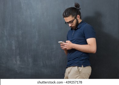 Picture Of Young Arab Man On Chalkboard Using Phone