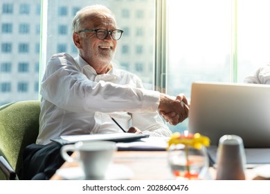 Picture Of Young Business Man Taking To His Older Business Partner. They Are In White Shirt And Black Tie. They Are In A Hotel Lobby. 