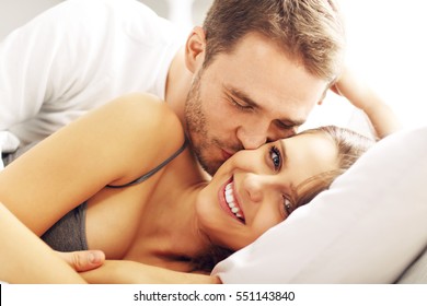 Picture of young couple kissing in bed 