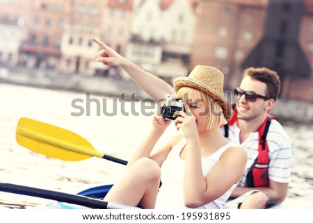 A picture of a young couple taking pictures in a canoe