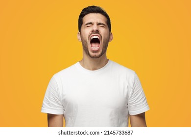 Picture Of Young European Caucasian Man Isolated On Yellow Background Standing With Eyes Shut And Mouth Open As If Screaming In Despair Or Being Extremely Exhausted