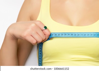 A picture of a young fit happy woman checking her breast measurement over white background.