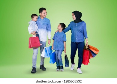 Picture Of Young Happy Family Carrying Shopping Bags While Walking Together In The Studio With Green Screen