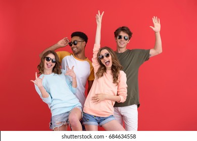 Picture Of Young Happy Group Of Friends Standing Isolated Over Red Background. Looking At Camera.