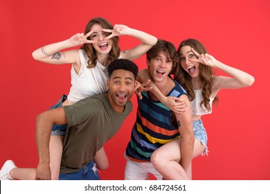 Picture Of Young Happy Group Of Friends Standing Isolated Over Red Background. Looking At Camera.