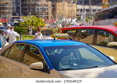 Picture of young man in cap and plaid shirt sitting in back seat in yellow taxi. Happy male getting into a cab. Businessman entering a taxi on city street - Powered by Shutterstock