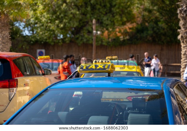Picture of young man in cap and plaid shirt\
sitting in back seat in yellow taxi. Happy male getting into a cab.\
Businessman entering a taxi on city\
street