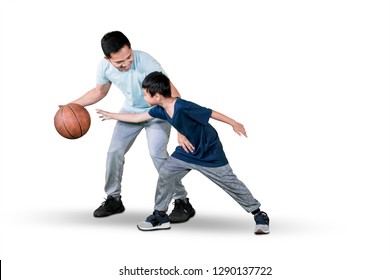 Picture Of A Young Man And His Son Playing Basketball While Exercising In The Studio, Isolated On White Background