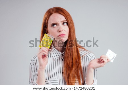 picture of young redhead be lost in thought businesswoman in striped shirt with one pack of condom and birth control pills choosing thinking white background studio