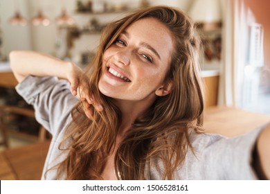 Picture of young smiling beautiful positive ginger woman indoors at home take selfie by camera. - Powered by Shutterstock