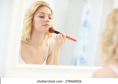 A Picture Of A Young Woman Applying Face Powder In The Bathroom