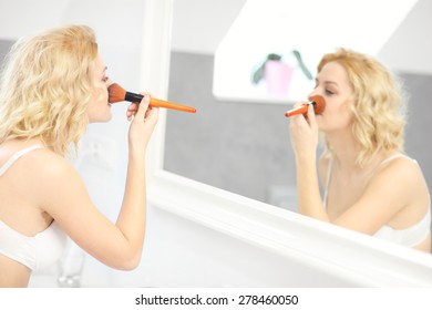 A Picture Of A Young Woman Applying Face Powder In The Bathroom