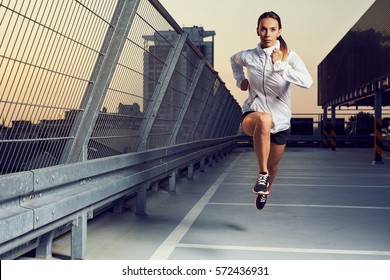 Picture of young woman sprinting on the rooftop parking garage - Powered by Shutterstock