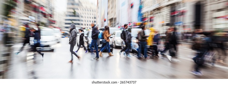 picture with zoom effect of a crowd of pedestrians crossing a street in the rainy city