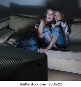 Pictures In A Living Room Of Two Young Girls Sitting On A Couch Watching On Tv A Scary Movie