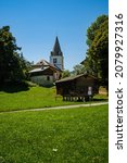 Picturesque alpine summer landscape view with small white church, wooden buildings, trees and green pastures - Cergnat, Ormont-Dessous near Aigle in Swiss canton of Vaud, Switzerland