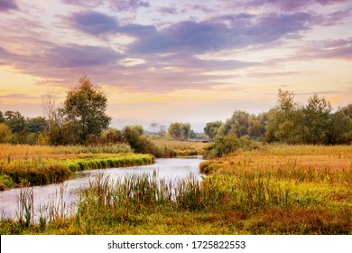 Picturesque autumn landscape with river and cloudy sky at sunset