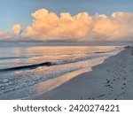 A picturesque beach scene with calm waters of Sanibel Island and fluffy white clouds.