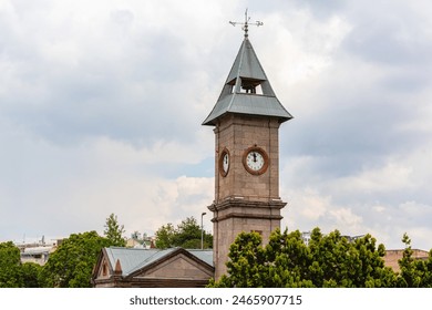 Picturesque clock tower in Kayseri, Turkey, set against a cloudy sky with lush greenery in the foreground. Kayseri, Turkey (Turkiye) - Powered by Shutterstock