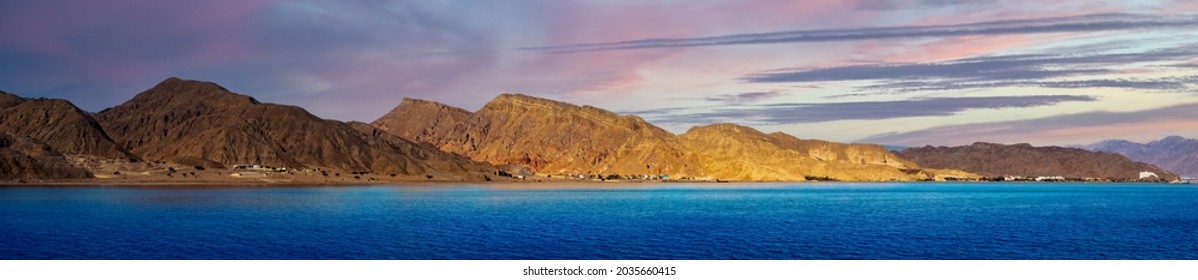 Picturesque coast of the Red Sea in the Gulf of Aqaba on the border of Egypt and Israel, Taba region, Sinai. Panoramic landscape with mountain ranges and beautiful cloudy sky at sunset. - Powered by Shutterstock
