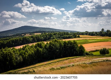 A picturesque countryside panorama of hilly, golden fields, green forest and Lysica Mountain. Swietokrzyskie Mountains, Poland.