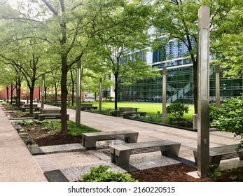 Picturesque courtyard in an office complex surrounded by green trees, grass and parkway benches.