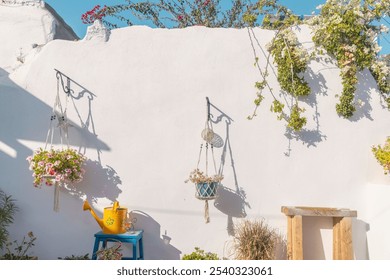 In a picturesque courtyard on Paros, vibrant hanging flower pots and a bright yellow watering can complement the whitewashed wall, creating a serene atmosphere beneath the sunny sky. - Powered by Shutterstock