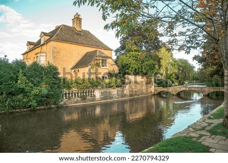 Picturesque English village Bourton-on-the-Water in the touristic rural region of The Cotswolds, England. Beautiful town scene with old house, river and stone bridge.