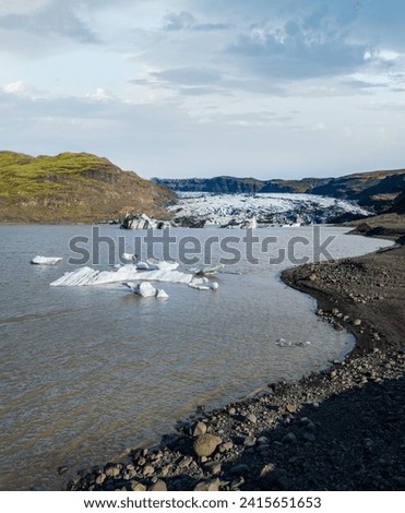 Sólheimajökull picturesque glacier in southern Iceland. The tongue of this glacier slides from the volcano Katla. Beautiful glacial lake lagoon with blocks of ice and surrounding mountains.