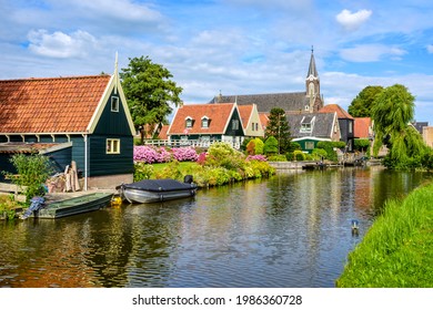 Picturesque idyllic De Rijp village in North Holland, Netherlands, view of characteristic wooden houses with red tiled roofs and flower beds and the church reflecting in a river - Shutterstock ID 1986360728