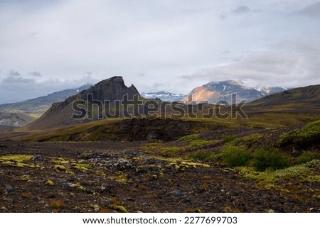 The picturesque landscape along a famous Laugavegur hiking trail. Amazing Icelandic landscape of volcanic mountains in cloudy weather with green grass and moss. Iceland in august. 