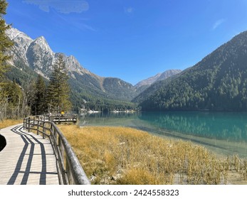 picturesque landscape of Lake Antholz with a wooden boardwalk along the shore and surrounded by high mountains
