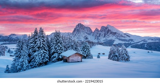Picturesque landscape with small wooden log cabin on meadow Alpe di Siusi on sunrise time. Seiser Alm, Dolomites, Italy. Snowy hills with orange larch and Sassolungo and Langkofel mountains group - Powered by Shutterstock