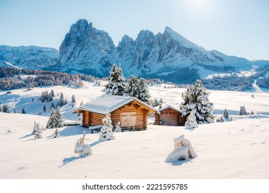 Picturesque landscape with small wooden log cabin on meadow Alpe di Siusi on sunrise time. Seiser Alm, Dolomites, Italy. Snowy hills with orange larch and Sassolungo and Langkofel mountains group - Shutterstock ID 2221595785