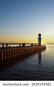 Picturesque lighthouse at end of pier, seaside dock, sunset on the ocean, peaceful