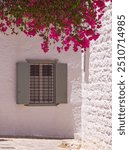 Picturesque mediterranean window with bougainvillea in sunny day, streets of Hydra, Saronic Gulf, Aegean Sea, Greece 